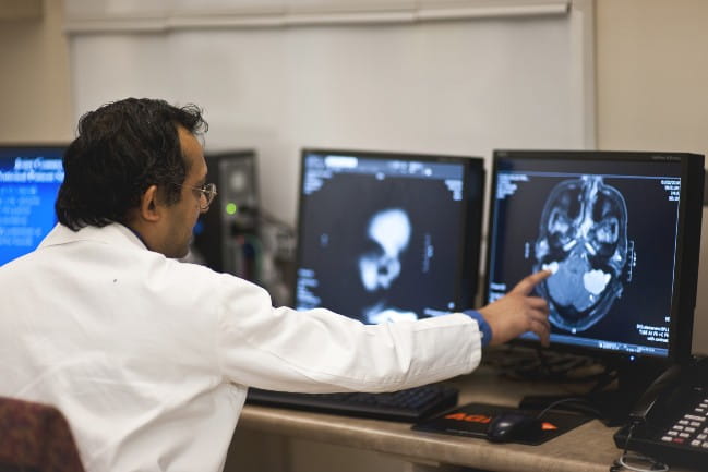 Care team member studying scan of brain on a computer monitor.